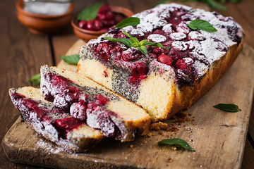 Cherry poppy seed cake dusted with powdered sugar on a wooden table