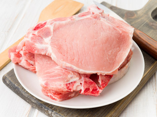 Raw pork chops stacked in white wood