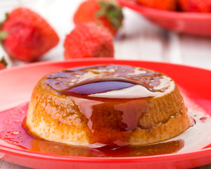 Homemade flan with strawberries, on red