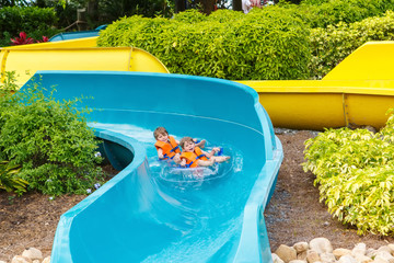 excited children in water park riding on slide with float
