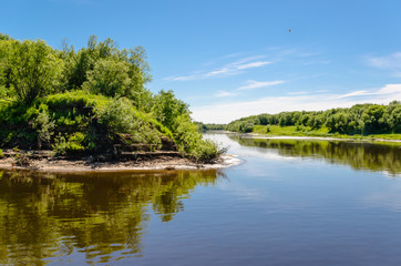 Calm river with wooded, sandy shores