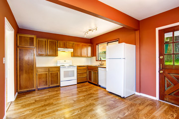 Kitchen room with woden cabinets, hardwood floor and red walls.