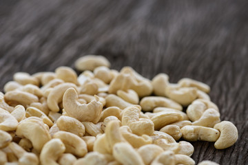 close up of raw cashew nuts on wooden table with space