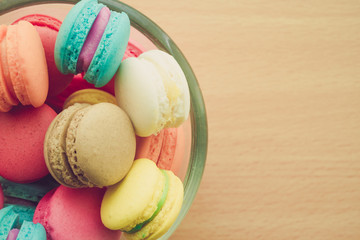 Colorful france macarons in glass cup on wooden background.