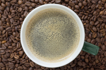 Coffee cup view from top on the background of coffee beans
