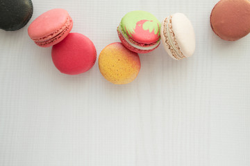 Colorful france macarons on white wooden background.