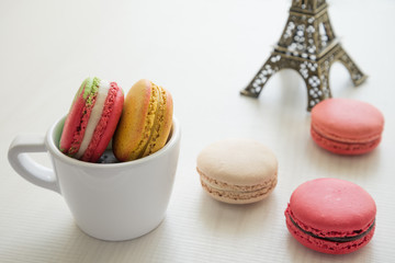 Colorful france macarons and cup on white wooden background.