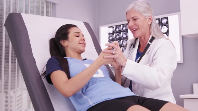 Female college sports athlete with female doctor reviewing concussion