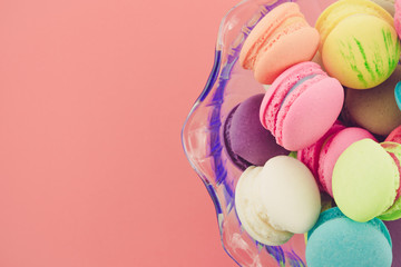 Colorful france macarons in glass cup on pink background