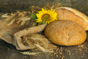 Bread with ears of wheat and sunflowers on a rough cloth