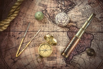 Old compass and telescope on vintage map. Retro style.