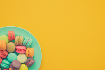 Colorful france macarons on yellow background.