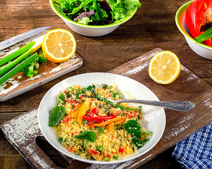 Couscous with vegetables on wooden background.
