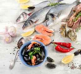 Fresh fish and other seafood on white wooden background.