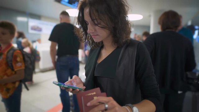 A young woman is checking news in her phone and smiling