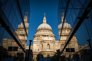St Paul&rsquo;s cathedral seen from a narrow alley enclosed by glass buildings and reflecting in the shiny surface at morning dawn