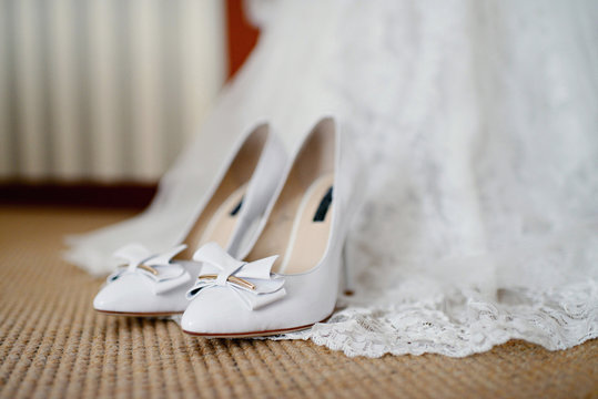 Beautiful white wedding dress and shoes for bride indoors. Beauty of bridal gown for marriage. Female lace clothes for celebration