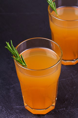 Apple cider garnished with rosemary and apples on dark background