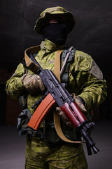 Soldier with Kalashnikov assault rifle/Portrait of soldier in black mask with a gun on dark background