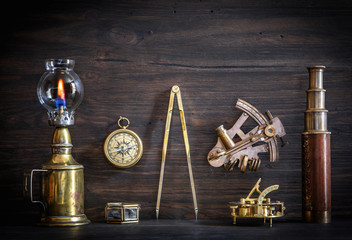 Compass, nautical lamp, sextant, telescope, old coins and a sundial on the captain's Desk. Retro...