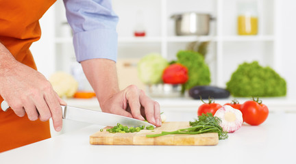 Obraz na płótnie Canvas Close-up of man's hands chopping onion on cutting board.