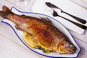 Whole grilled salmon fish on white wooden background. View from above, top studio shot