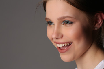 Smiling model with makeup. Close up. Gray background