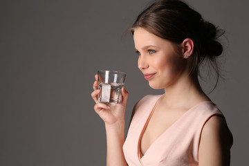 Lady with glass of water. Close up. Gray background