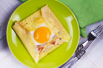 Egg on pancake with bacon and cheese in green plate. View from above, top studio shot