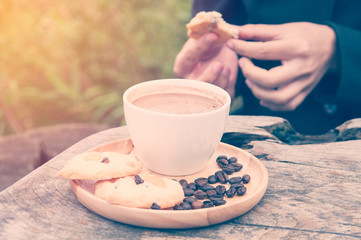 Woman in black eats cookies with hot coffee