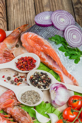 Fish filets and shrimps on rustic table with spices