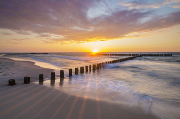 Sea landscape at sunset, sandy beach and cliff,waves breaking on the shore


