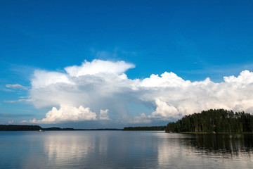 Glassy surface of the water, the reflection of the clouds and blue sky.