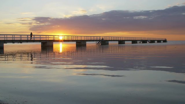 Yellow sunset where the sky is reflected in the sea. Silhouettes of bridge