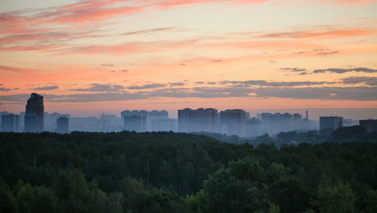 early sunrise and morning mist over woods and city