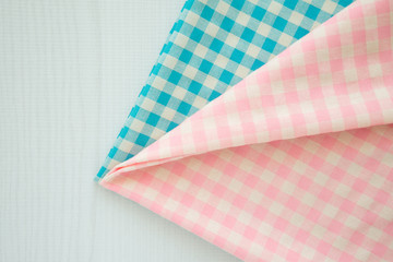 Blue and pink gingham tablecloth on white wooden table background