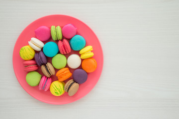 Colorful france macarons on white wooden background.