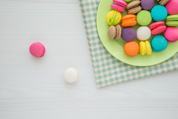 Colorful france macarons on green tablecloth and white table background