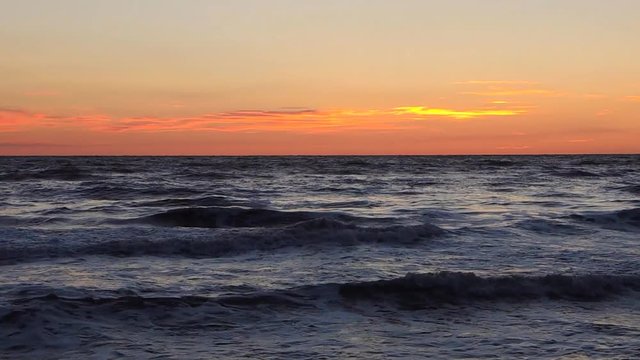Waves on sandy beach at sunrise. Italian coastline.
