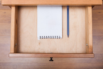 blue pen and squared notebook in open drawer