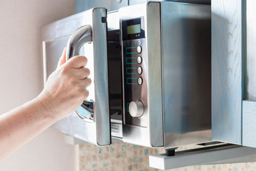 hand opens microwave oven for heating food