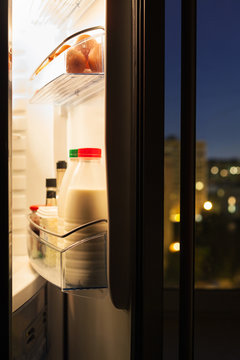 door of refrigerator with milk bottles in night