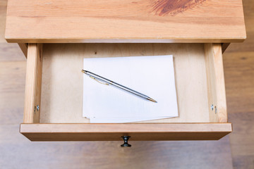 folded note and pen in open drawer
