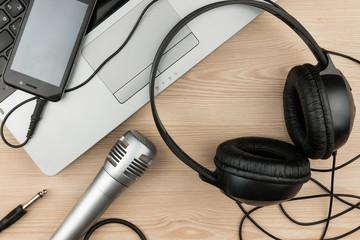 Laptop, microphone, headsets lies on a wooden table