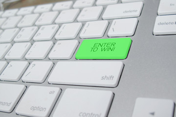 Close-up view on white conceptual keyboard - Enter to win (green key)