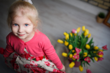 Portrait of a beautiful little girl with flowers on background of brick wall