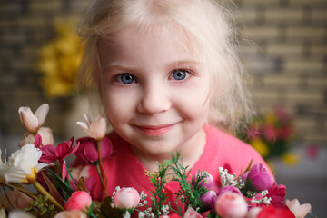 Obraz na płótnie Canvas Portrait of a beautiful little girl with flowers on background of brick wall