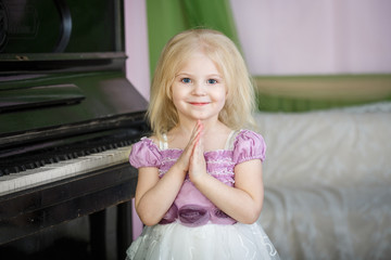 Portrait of a little girl with a beautiful dress near the piano