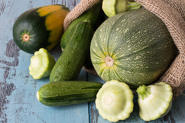 
Zucchini and squash.    Young freshly picked zucchini and squash in a sack on a blue wooden background.