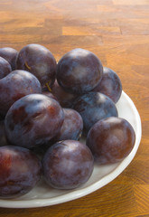 Obraz premium small plums on a white saucer